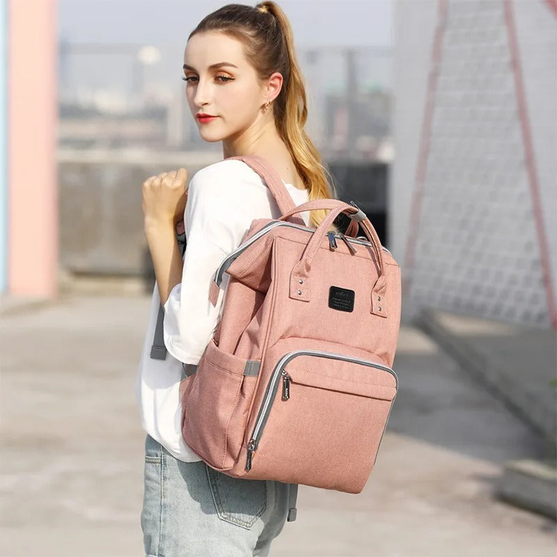 Femme avec sac à dos à langer convivial rose
