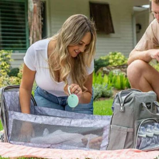 Mère joue avec enfant dans sac à dos à langer ergonomique gris