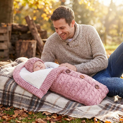 Père regarde poupon dans lange d'emmaillotage thermique plus rose